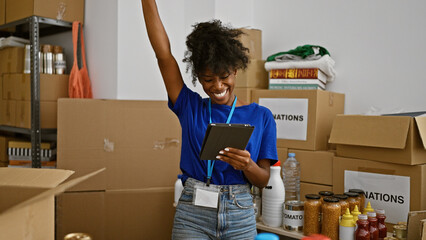 African american woman volunteer using touchpad celebrating at charity center