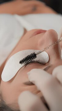 The vertical video depicts the work of a beautician with eyelashes as part of a beauty community, where professionalism is combined with an individual approach to each client in beauty salon closeup