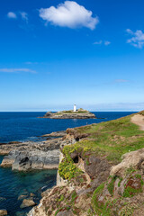 Looking over the rocky coastline towards Godrevy Lighthouse in Cornwall, on a sunny September day