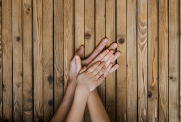 Family, mother, children holding hands together on a wooden background showing care. Close-up...