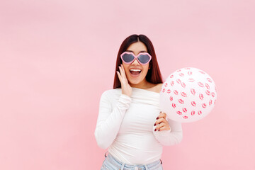 Amazed surprised asian woman in glasses holding balloon and looking at camera