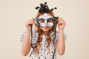 Child in a carnival masquerade mask. Festival, carnival, party. A little girl makes faces in a...