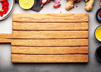 Food and cooking background with fresh raw vegetables. Wooden cutting board, paprika, zucchini, spices and ingredients for cooking Asian dishes with ginger, garlic, soy sauce and lime, top view
