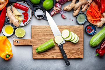 Food and cooking background. Gray table with chopped zucchini. Paprika, vegetables, spices and...