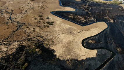 Aerial View of a Meandering River Through a Burnt Grassland After Fire