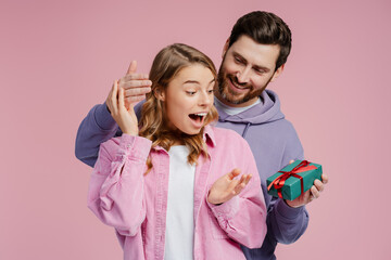 Portrait of smiling, excited couple, attractive man giving gift box to beautiful emotional woman  