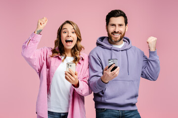 Portrait of overjoy hipster couple, man and woman wearing stylish colorful clothes, holding mobile...