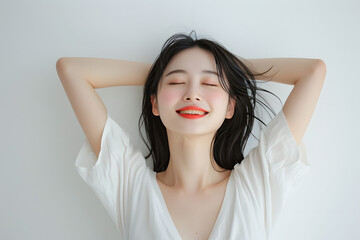 Fototapeta premium smiling asian woman with her arms raised above her head on white white background