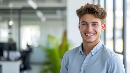 Fototapeta premium young handsome man with blue eyes on the background of a modern IT office, worker, programmer, professional, designer, guy, boy, portrait, smile, space for text, coworking, open space, people, person