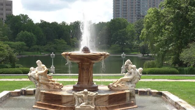 Marble fountain shooting up water in the middle of green grass and pond Cleveland art museum