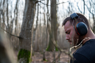 profil d'un bucheron au travail en forêt avec des brindilles qui volent