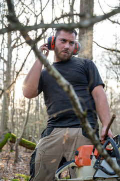 bucheron en plein travail dans une for&ecirc;t avec un casque anti bruit connect&eacute;