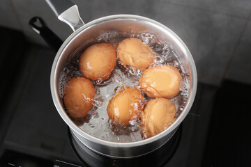 Chicken eggs boiling in saucepan on electric stove, above view