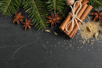 Different spices, nut and fir branches on gray table, flat lay. Space for text
