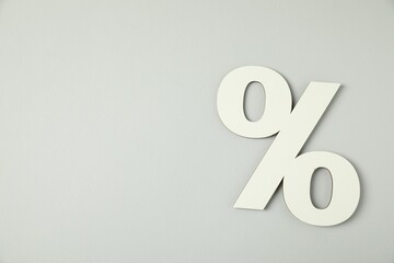 White percent sign on light grey background, top view. Space for text