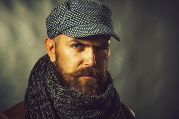 Closeup portrait of bearded man in leather jacket, woolen scarf and cap. Casual winter clothes....