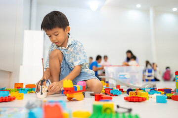Adorable preschool asian kid boy and girl enjoying play colorful building toy block