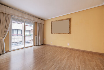 Empty room with walls painted a soft cream color, plaster moldings on the ceiling and a wall with sliding aluminum