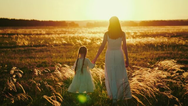 Child and mother choose suitable location for photo shot on field at sunset. Child with mother walks in field regretting father busy at work. Child shares with mother concerns about problems at school