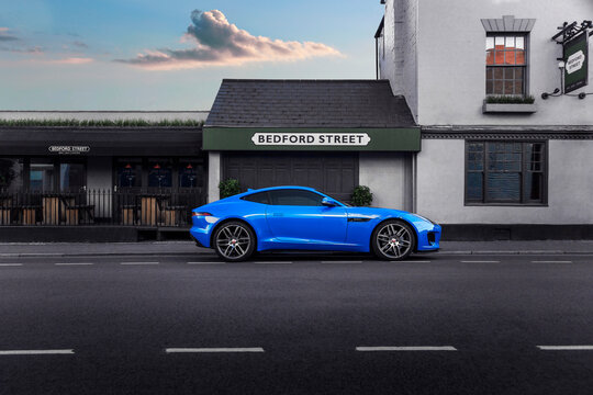 Leamington, UK - August 9 2020 : A Jaguar F-Type sports coupe in bright blue with modern urban backdrop and large wheels. No numberplate or people professionally retouched. Tata Motors Land Rover