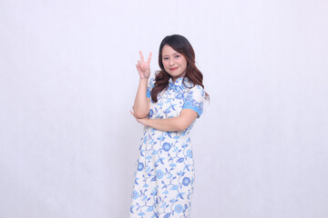 Beautiful smiling asian woman wearing modern chinese dress holding arms crossed or peace sign isolated on white background. happy Chinese New Year
