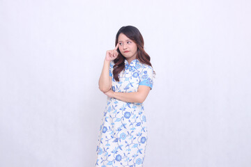 Beautiful serious asian woman wearing modern chinese dress arms crossed while thinking isolated on white background. happy Chinese New Year