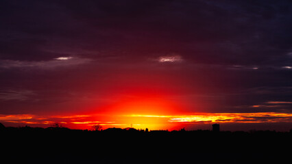 Obraz premium Magnificent orange landscape of the sunrise with heavy clouds.