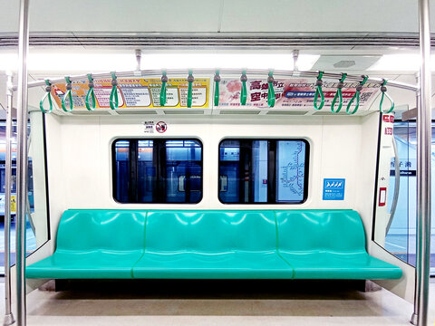 Kaohsiung, Taiwan - February 3, 2024: Kaohsiung Metro (KMRT) train interior seating area, departure station, bright train interior, empty seats. Passenger seatless train with green seats