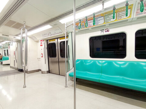 Kaohsiung, Taiwan - February 3, 2024: Kaohsiung Metro (KMRT) train interior seating area, departure station, bright train interior, empty seats. Passenger seatless train with green seats