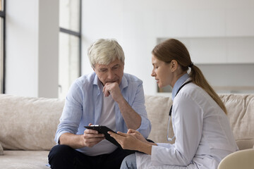 Serious doctor woman in white coat giving treatment recommendation to older man, explaining medical checkup results, diagnosis, therapy instructions, meeting with patient at home - Powered by Adobe