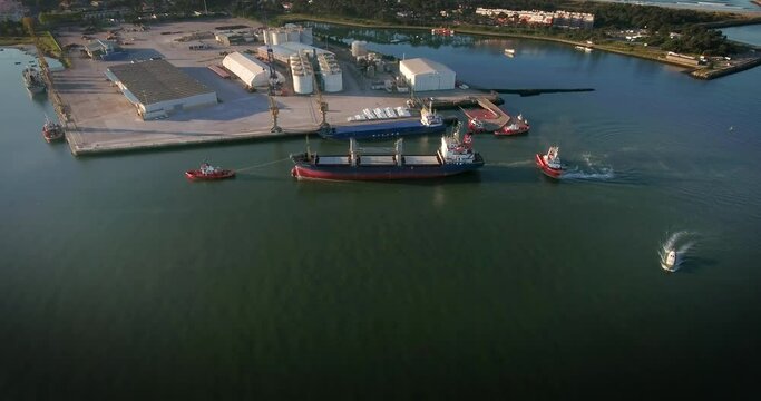 Aerial view of a Ship being towed to the harbour by tugboats