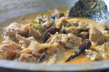 The process of cooking rendang in a traditional stove uses charcoal