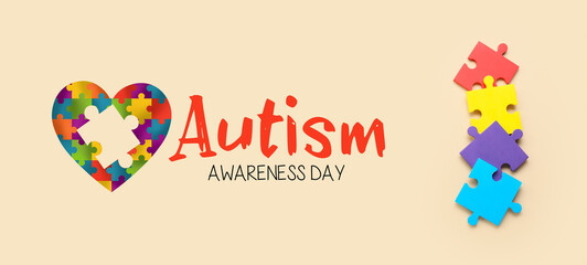Colorful puzzle pieces and text AUTISM AWARENESS DAY on beige background