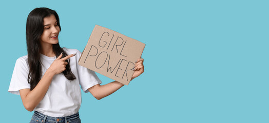 Young woman pointing at cardboard with text GIRL POWER on blue background with space for text....