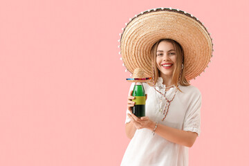 Young woman in sombrero hat with drink on pink background. Mexico's Day of the Dead (El Dia de Muertos) celebration