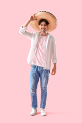 Young Mexican man in sombrero on pink background