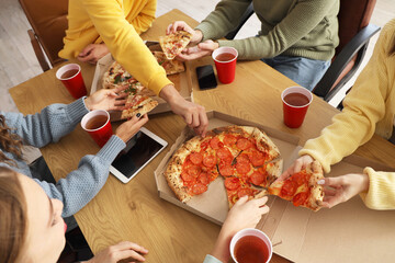Group of young colleagues eating pizza at office party, closeup