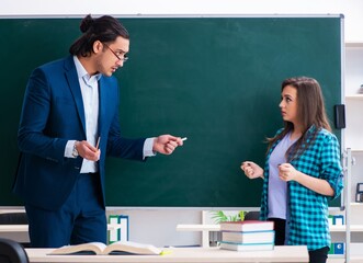 Young handsome teacher and female student in the classroom