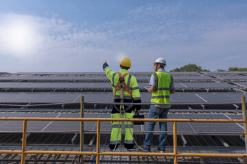 Naklejka premium workers at work. Couple worker discuss on solar rooftop. engineer work on sustainable solar cell on roof of factory.