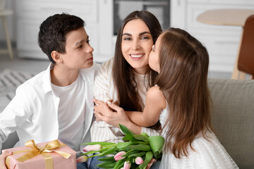 Little children greeting their mother with gifts at home