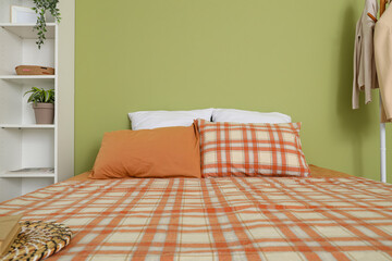 Big bed with soft pillows near green wall in bedroom