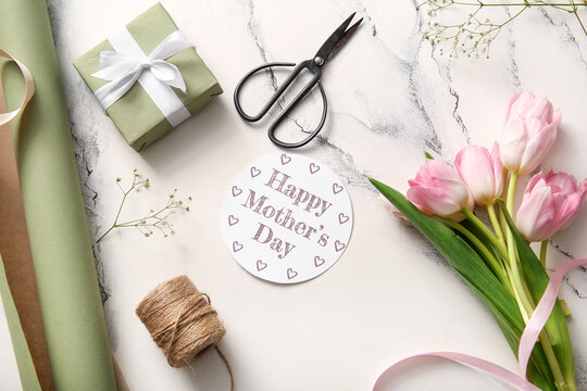 Card with text HAPPY MOTHER'S DAY, gift box,  scissors, threads and flowers on light background