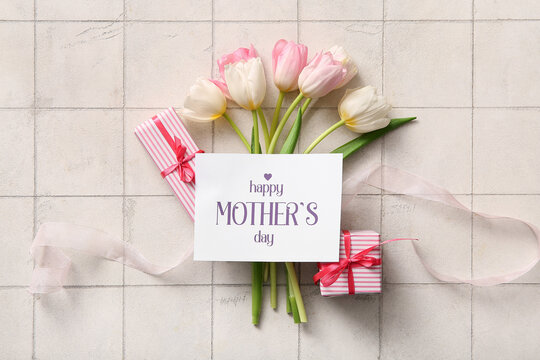 Card with text HAPPY MOTHER'S DAY, gift boxes and tulip flowers on light tile background