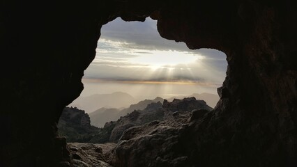 The radiant sun beams through a majestic mountain cave, casting a warm glow into its depths.