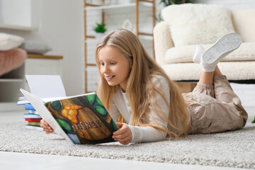Little girl reading book on floor at home
