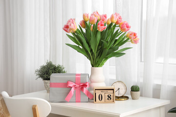 Calendar with date of International Women's Day, tulips and gift box on table in room