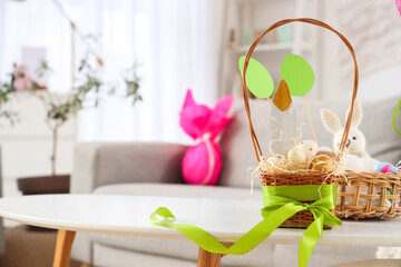 Wicker basket with Easter eggs on table in living room, closeup