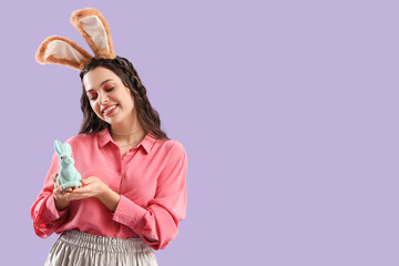 Beautiful woman in bunny ears with Easter rabbit on lilac background