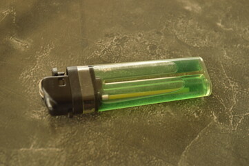 Classic blue green fire lighter for burning purposes. Suitable for lighting a fire or cigarette isolated on stone surface background.
