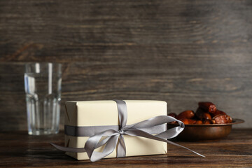 Gift box with glass of water and dried dates for Ramadan on wooden table